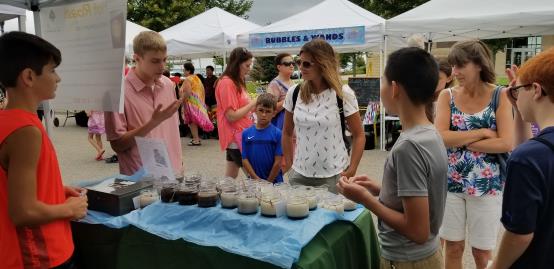 Harborfest event scene with students and community members visiting a nonprofit exhibitor table.